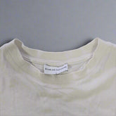 White t-shirt with a brand label on a tiled floor
